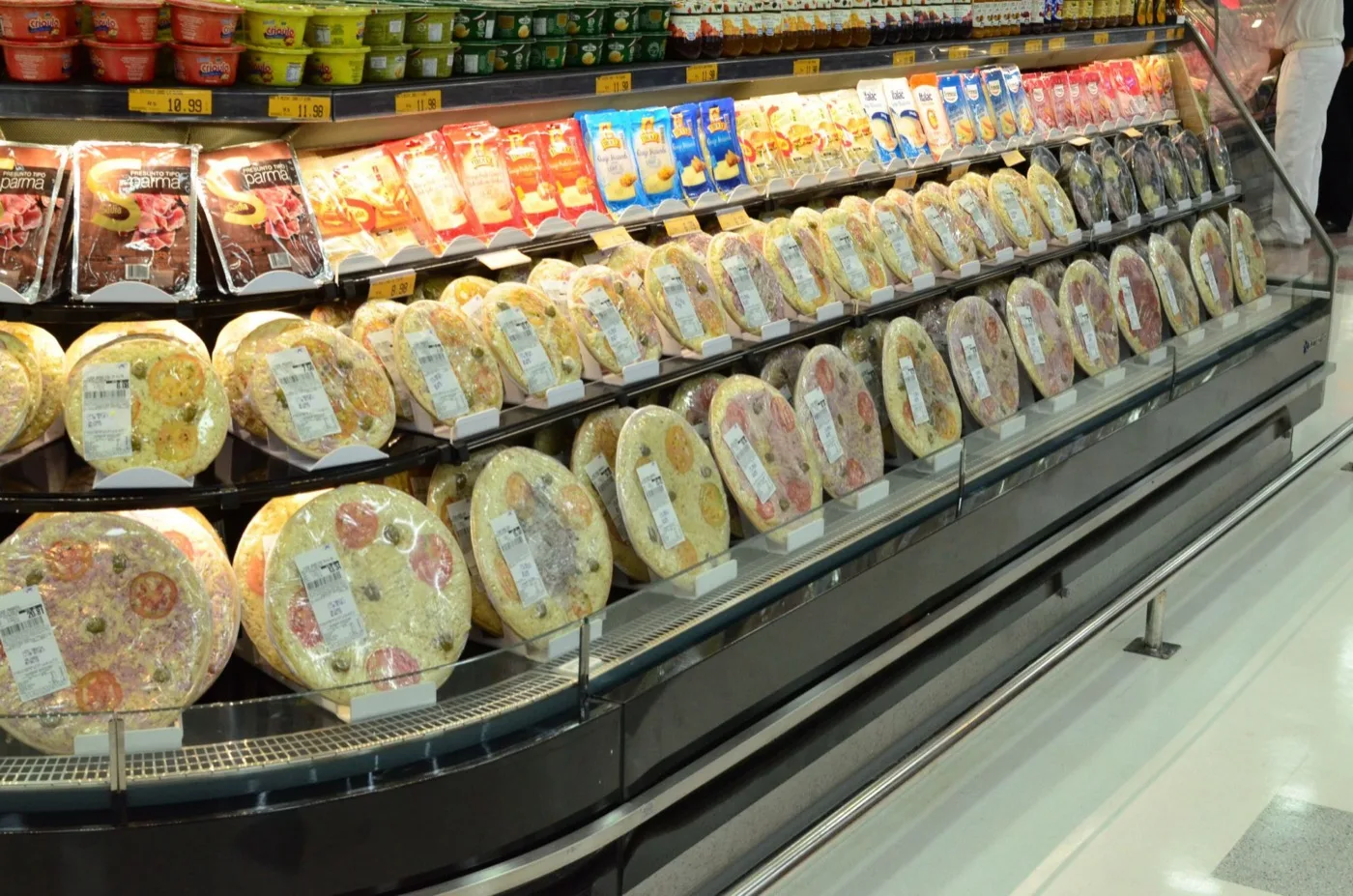 Rotisserie com pizzas e frios em vitrine